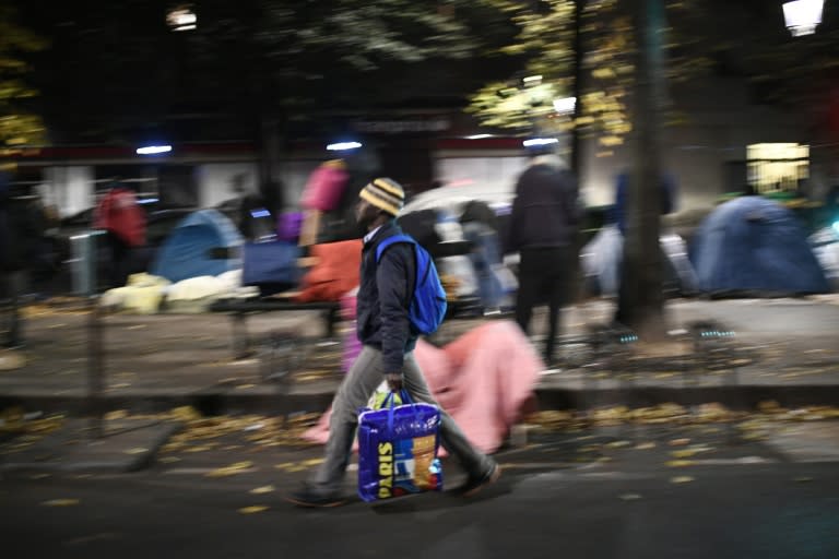 Migrants collect their belongings on the Avenue de Flandre during the evacuation of a makeshift camp in Paris on November 4, 2016