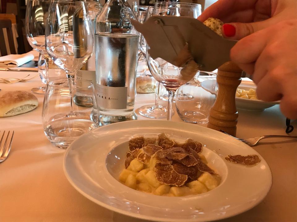 In this photo taken on Sunday, Nov. 10, 2019, a waitress grates a white truffle onto a warm dish of potato gnocchi with a cheese sauce at a restaurant in Grinzane Cavour, Italy, near a castle that is the site of an annual white truffle auction. White truffles are highly prized for their rarity and unique aroma, and are best eaten raw atop warm dishes, like poached eggs, risotto or egg noodles. (AP Photo/Colleen Barry)