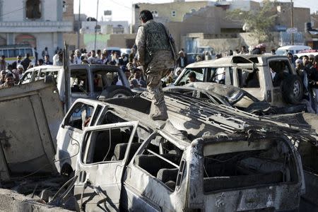 A Houthi fighter walks on a vehicle damaged by an air strike at a residential area near Sanaa Airport March 26, 2015. REUTERS/Khaled Abdullah