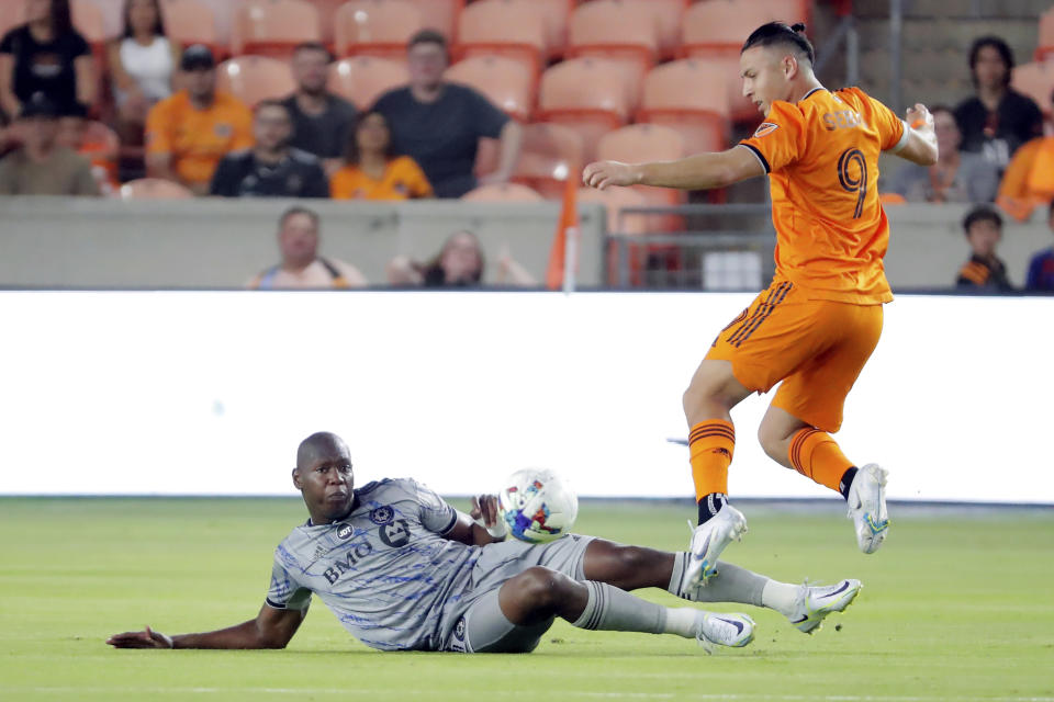 CF Montreal defender Kamal Miller, left, attempts to slide-tackle Houston Dynamo forward Sebastian Ferreira (9) who jumps over him during the first half of an MLS soccer match Saturday, Aug. 13, 2022, in Houston. (AP Photo/Michael Wyke)