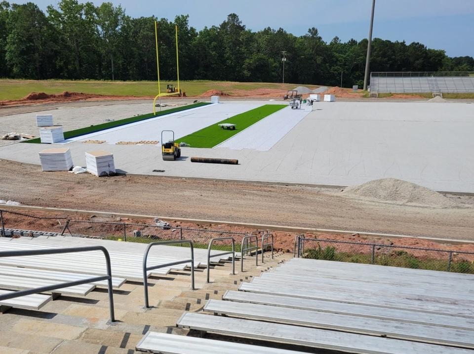 The first pieces of green artificial turf are laid on Warrior Field earlier this year.