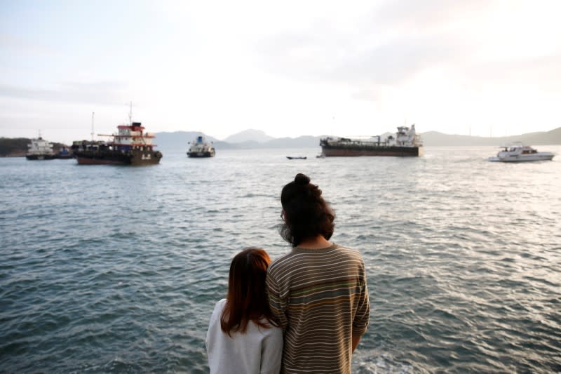 Derek Tai and his girlfriend Ann walk by the sea during sunset in Hong Kong