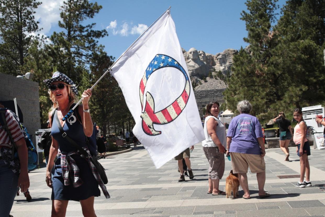 A Donald Trump supporter holding a QAnon flag visits Mount Rushmore National Monument on July 01, 2020 in Keystone, South Dakota: Scott Olson/Getty Images