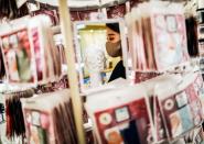 An employee of Cox Co, the operation company of the face-mask speciality shop Mask.com, holding a luxury face mask decorated with the diamond, platinum and Swarovski crystals is refelected on a mirror in Tokyo