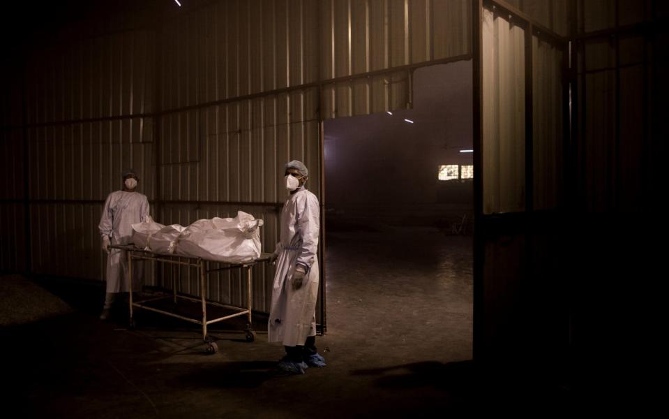 Workers transfer the body of a patient who died of coronavirus for his last rites at a crematorium in New Delhi, India - Anindito Mukherjee/Getty Images