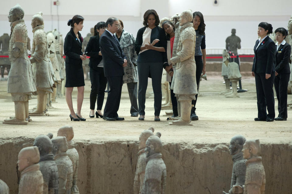 U.S. first lady Michelle Obama, center, checks a terracotta warrior as she visits Qinshihuang Terracotta Warriors and Horses Museum with her daughters, Malia, third right, and Sasha, fourth right, and her mother, Marian Shields Robinson, fourth left, in Xi'an, in northwestern China's Shaanxi province, Monday, March 24, 2014. (AP Photo/Alexander F. Yuan)