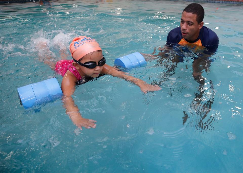 Nora Deguzman, 4, practices swimming with some help from a float and guidance from her coach, Rodion Davelaar, at AQUAfin Swim School in Orange City on Thursday, Aug. 18. Davelaar, a former Olympian, and his wife opened the location in July.