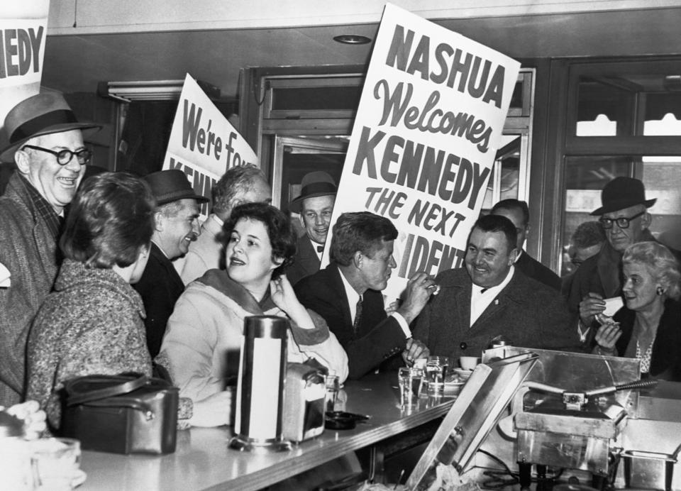 John F. Kennedy sits at a counter with some of his supporters while campaigning for president in a Nashua, New Hampshire (Corbis via Getty Images)