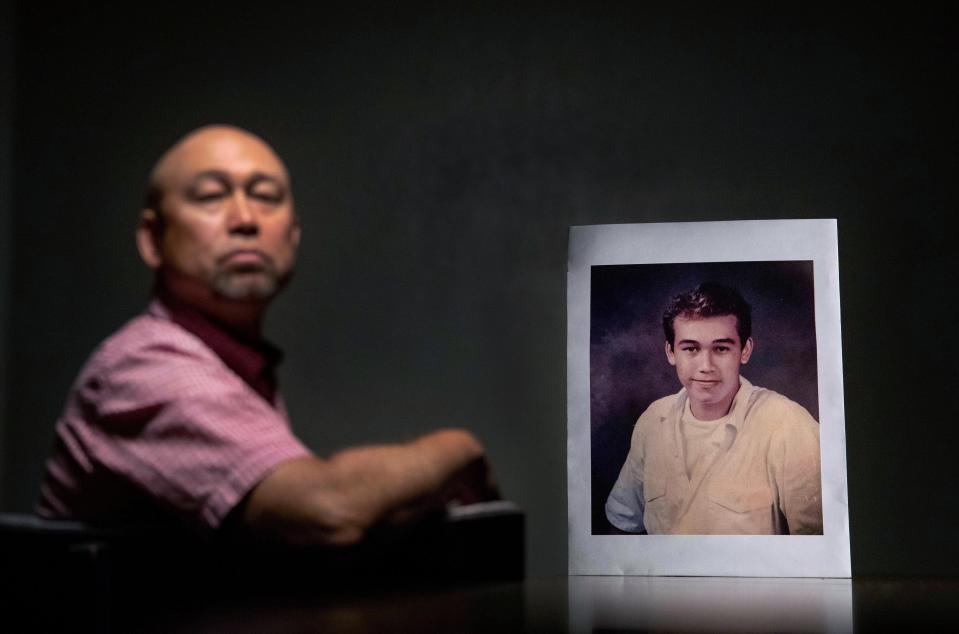 Robby Perez, 48, in New Orleans on Wednesday, June 12, 2019, sits beside a photo of himself when he was 14 years old, the age when he says in a lawsuit he was sexually abused as an altar boy in Guam by David Anderson, a former priest now living in Hawaii. Perez says he endured five years of sexual abuse, never telling anyone. Toward the end, Perez says, he fell in love with the priest. But when he professed his feelings, Anderson ended their relationship, saying he had to put God first. When reached by the AP, Anderson said, "I was young, the person was young... It's a long, long time ago." (AP Photo/David Goldman)