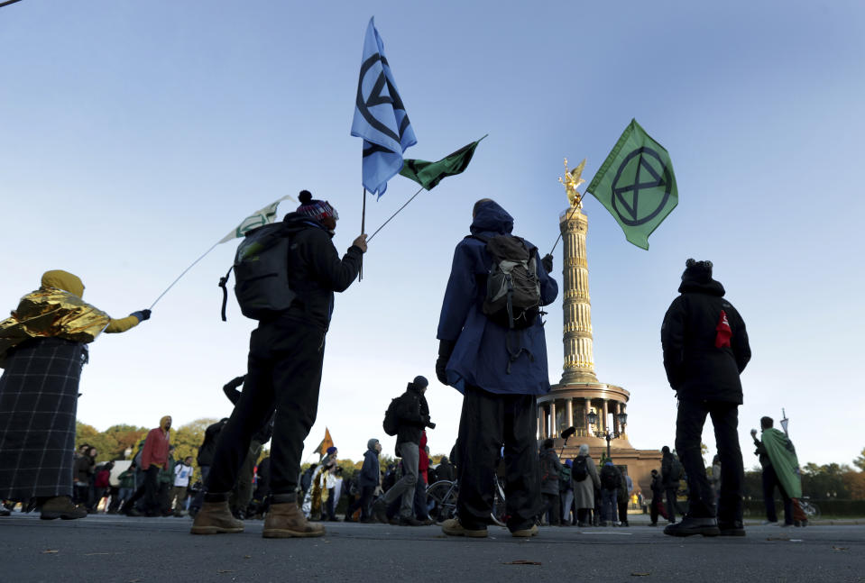 Supporters of the 'Extinction Rebellion' movement block a road at the Victory Column in Berlin, Germany, Monday, Oct. 7, 2019. The activists want to draw attention on the climate protest by blocking roads and with other acts of civil disobedience in Berlin and other cities around the world. (AP Photo/Michael Sohn)