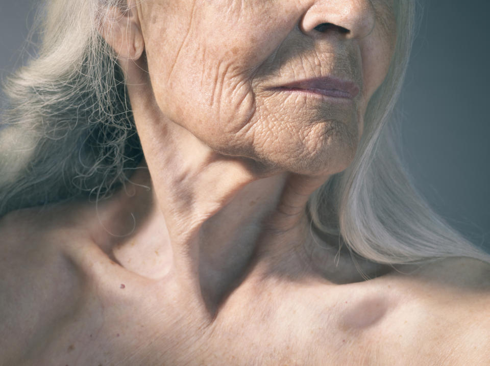 Close-up of an elderly person's face and neck showing detailed skin texture and wrinkles, indicating aging. The person is looking slightly to the side