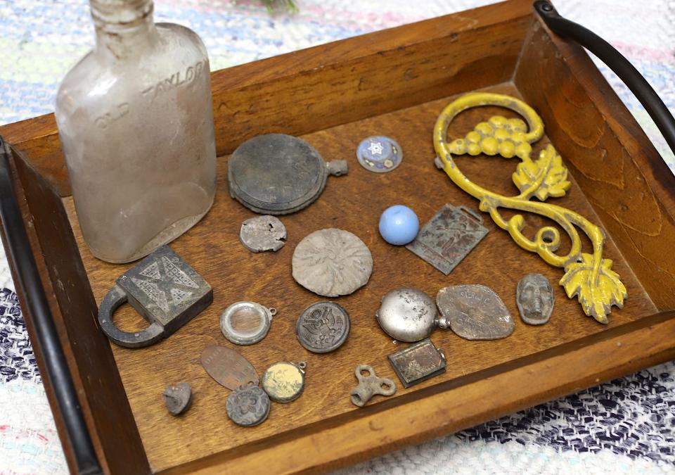 A collection of some of the items Caleb Colter found, which includes a WWI button, with his metal detecting gear is shown Thursday, Dec. 1, 2022, at his home in West Burlington.