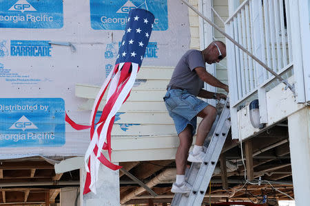 A man climbs down a ladder where stairs used to be, after Hurricane Irma in Big Pine Key, Florida, U.S., September 18, 2017. REUTERS/Carlo Allegri