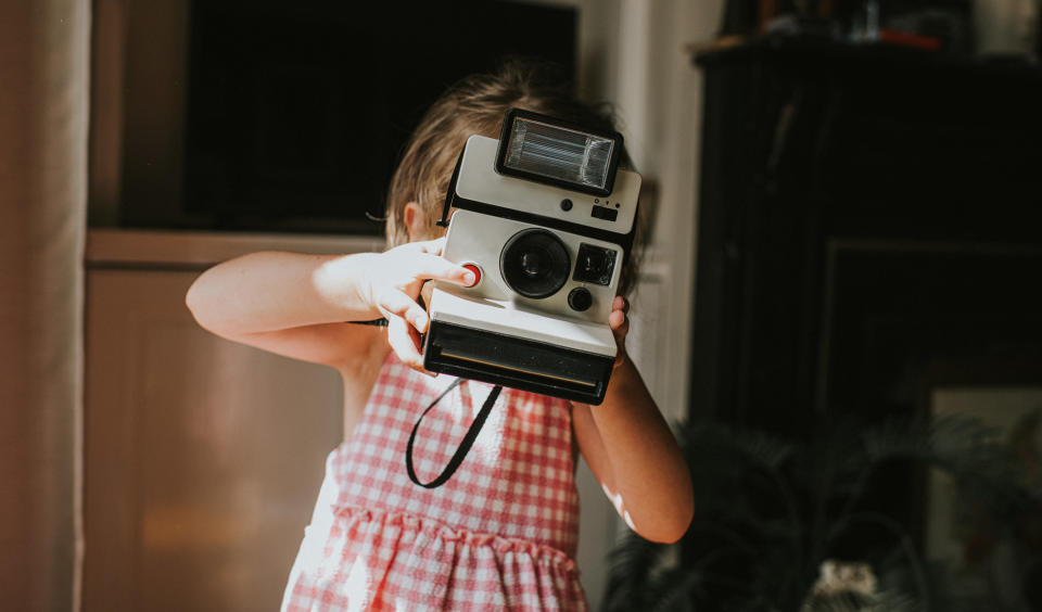 criança segura uma câmera polaroid