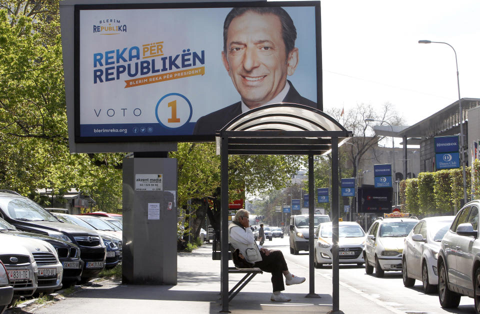 A man waits for a bus by an election poster of Blerim Reka, a candidate for two smaller ethnic Albanian opposition parties, with the inscription in Albanian reading "Reka for Republic", in a street in Skopje, North Macedonia, Friday, April 19, 2019. North Macedonia holds the first round of presidential elections on Sunday, a vote seen as key test for the center-left government's survival in a society deeply divided after the country changed its name to end a decades-old dispute with neighboring Greece over use of the term "Macedonia". (AP Photo/Boris Grdanoski)