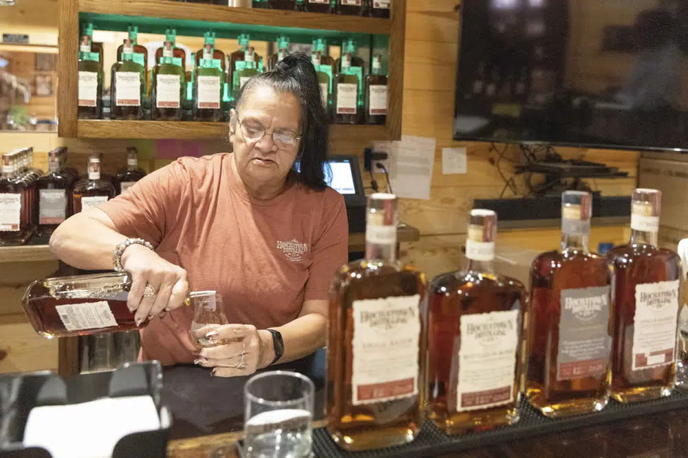 Bartender June Davis pours drinks inside the Hochatown Distilling Co. bar in Broken Bow, Okla. on Thursday, April 20, 2023. (AP Photo/Alonzo Adams)