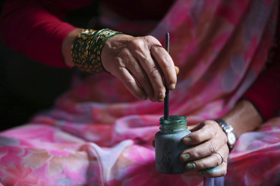 In this July 31, 2019, photo, Tej Kumari Chitrakar mixes color to make traditional paintings ahead of Naag Panchami festival at her residence in Bhaktapur, Nepal. Chitrakar families in the Nepalese capital of Kathmandu were renowned traditional painters and sculptors who depicted gods and goddesses on temples, masks of Hindu deities and posters for various religious celebrations. For Tej Kumari and her husband it is a struggle to keep the dying art alive against the modern mass produced prints. (AP Photo/Niranjan Shrestha)