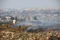 FILE PHOTO: Israeli soldiers are seen near fire burns in scrubland near the Gaza Strip, in an area where Palestinians have been causing blazes by flying kites and balloons loaded with flammable material across the border between Israel and the Gaza Strip