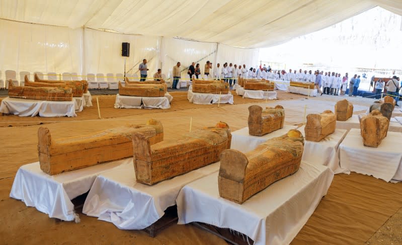 Archaeologists stand around painted ancient coffins at Al-Asasif necropolis, unveiled by Egyptian antiquities officials in the Valley of the Kings in Luxor