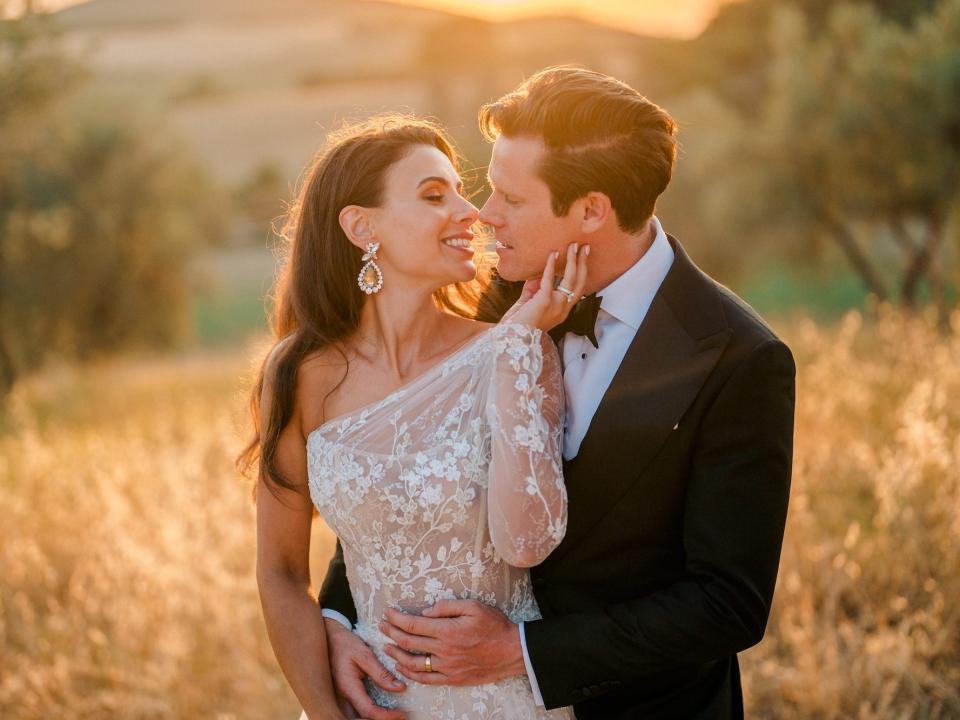 A bride and groom look at each other at sunset.