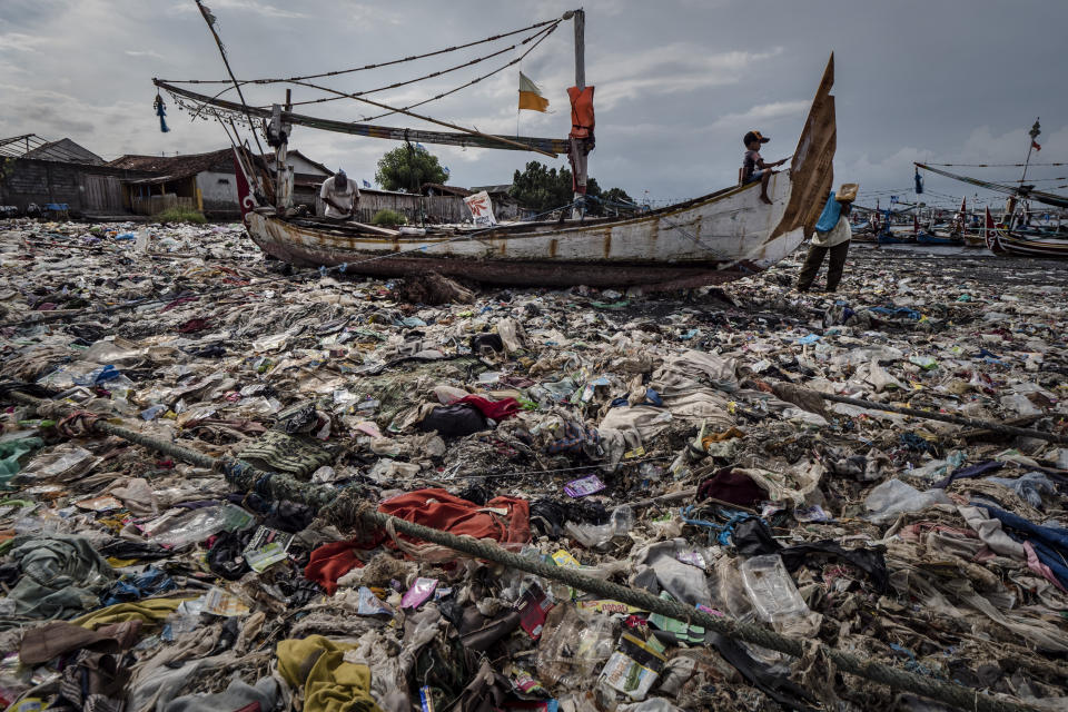 A boy paints a boat in a beach filled with plastic waste at Muncar port in Banyuwangi, East Java on March 4, 2019, in Indonesia. (Photo: ULET IFANSASTI FOR HUFFPOST)