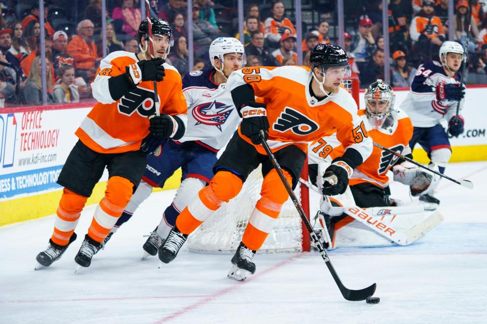 Philadelphia Flyers' Adam Ginning, front right, skates the puck up the ice as he goes past goalie Carter Hart, second from right, during the third period the team's NHL hockey game against the Columbus Blue Jackets, Tuesday, April 11, 2023, in Philadelphia. The Flyers won 4-3 in overtime. (AP Photo/Chris Szagola)