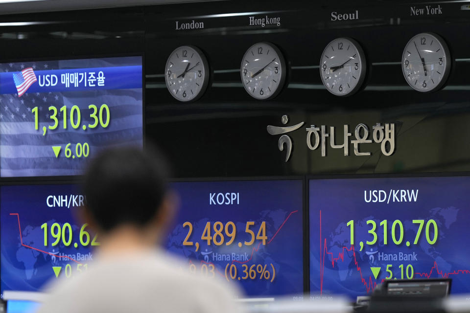 A currency trader walks by the screens showing the Korea Composite Stock Price Index (KOSPI), center, and the foreign exchange rate between U.S. dollar and South Korean won at a foreign exchange dealing room in Seoul, South Korea, Wednesday, April 5, 2023. Asian shares were trading mixed Wednesday following a decline on Wall Street after reports on the U.S. economy came in weaker than expected. (AP Photo/Lee Jin-man)