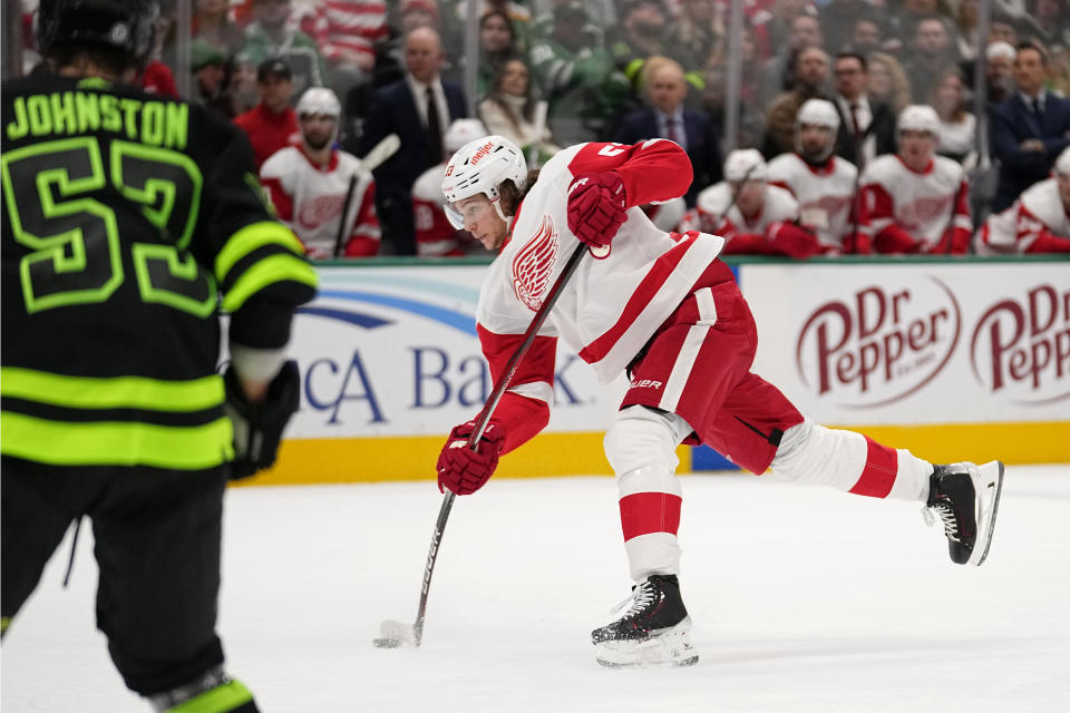 Detroit Red Wings defenseman Moritz Seider takes a shot as Dallas Stars center Wyatt Johnston, left, looks on in the second period of an NHL hockey game, in Dallas, Monday, Dec. 11, 2023. (AP Photo/Tony Gutierrez)