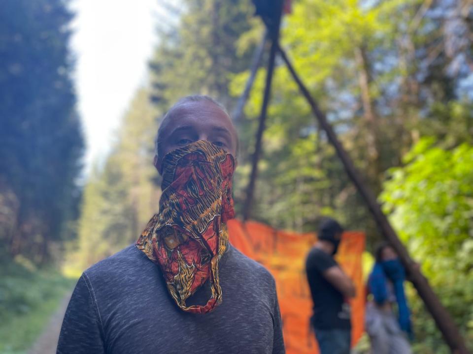 Kyle Grimm, a Savage Patch member, stands in front of a structure protesters built on a logging road.