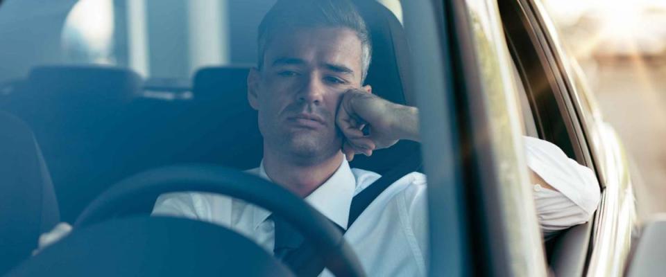 Pensive disappointed businessman sitting in his car and thinking with hand on chin