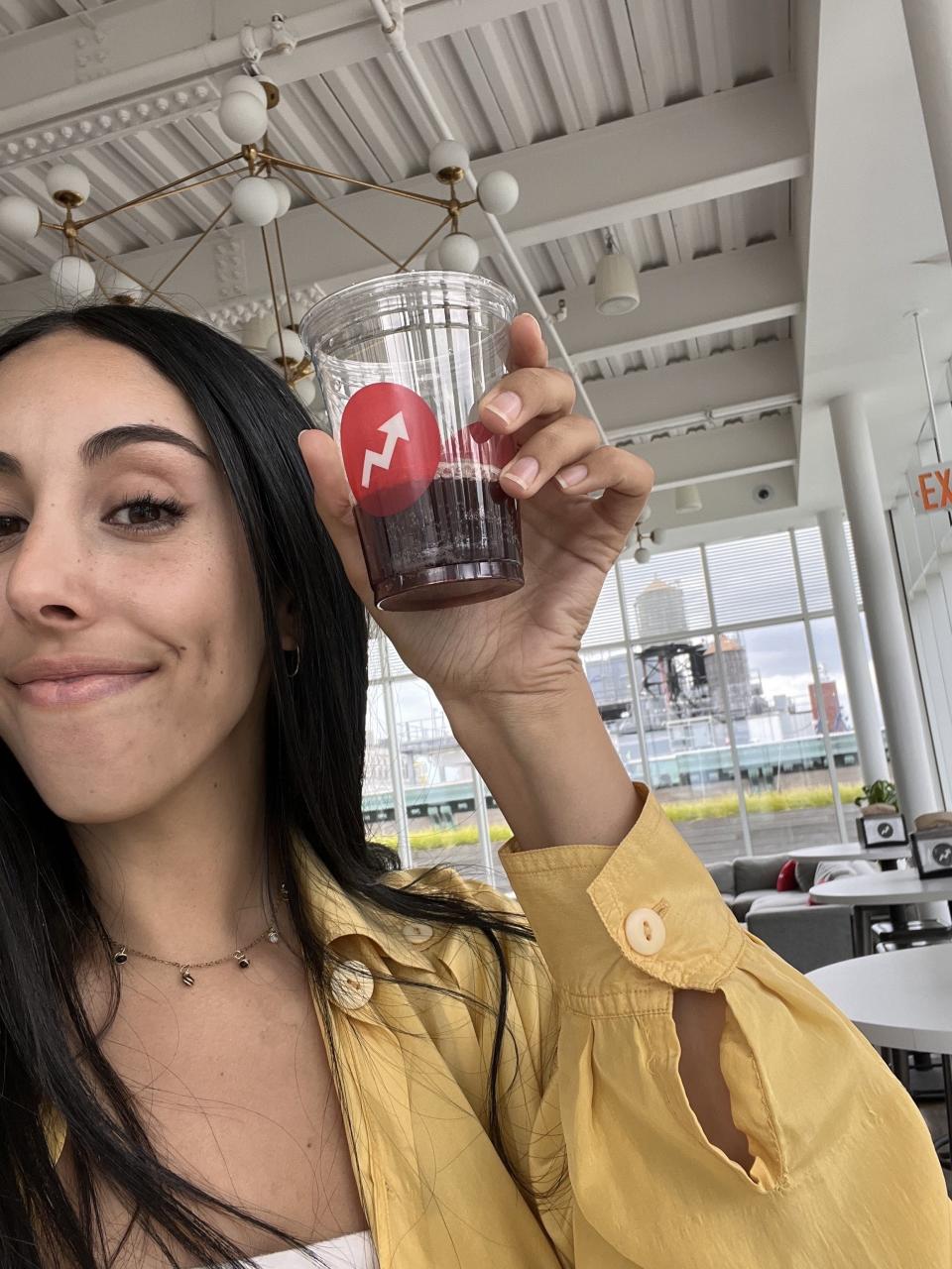 A woman holding a plastic cup containing a beverage