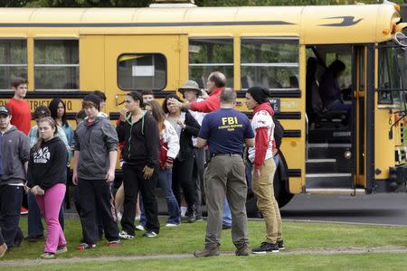 Students exit a bus with an FBI agent (R) speaking to students as they arrive at Shoultes Gospel Hall church after a student opened fire at Marysville-Pilchuck High School in Marysville, Washington October 24, 2014. REUTERS/Jason Redmond