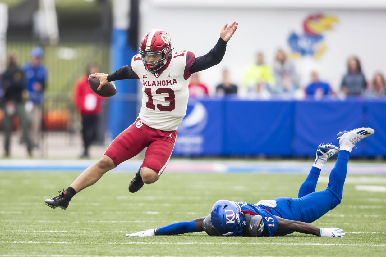 LAWRENCE, KS - OCTOBER 23: Oklahoma Sooners quarterback Caleb Williams (13) leaps over the tackle attempt of Kansas Jayhawks defensive end Kyron Johnson (15) during the game between the Kansas Jayhawks and the Oklahoma Sooners on Saturday October 23, 2021 at Memorial Stadium in Lawrence, KS.  (Photo by Nick Tre. Smith/Icon Sportswire via Getty Images)