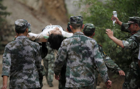 Paramilitary policemen carry an injured woman with a stretcher after an earthquake hit Ludian county of Zhaotong, Yunnan province August 3, 2014. REUTERS/China Daily