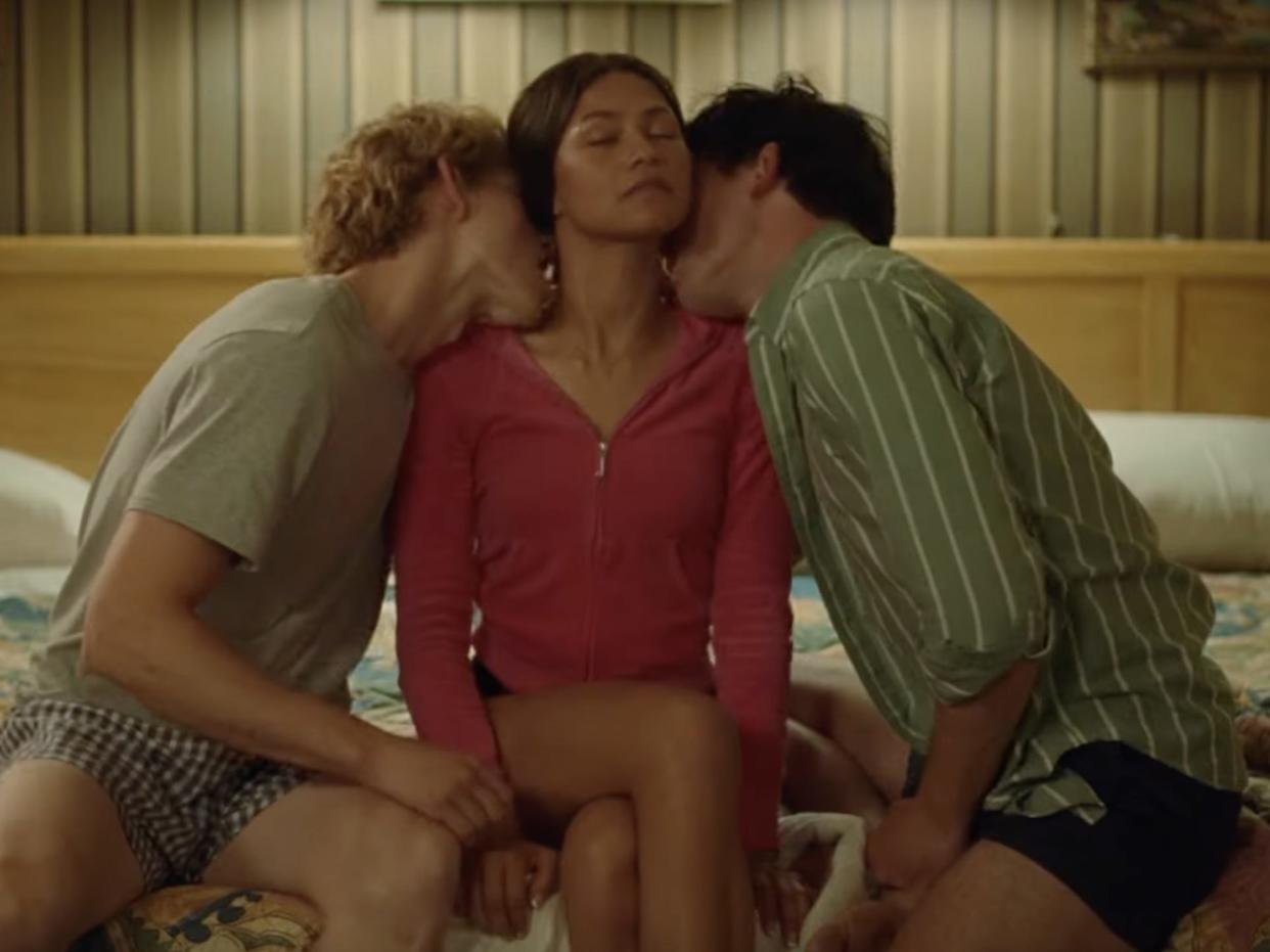 Zendaya being kissed by two guys on a bed
