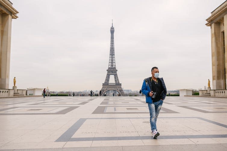 Man walking in front of deserted Eiffel Tower.