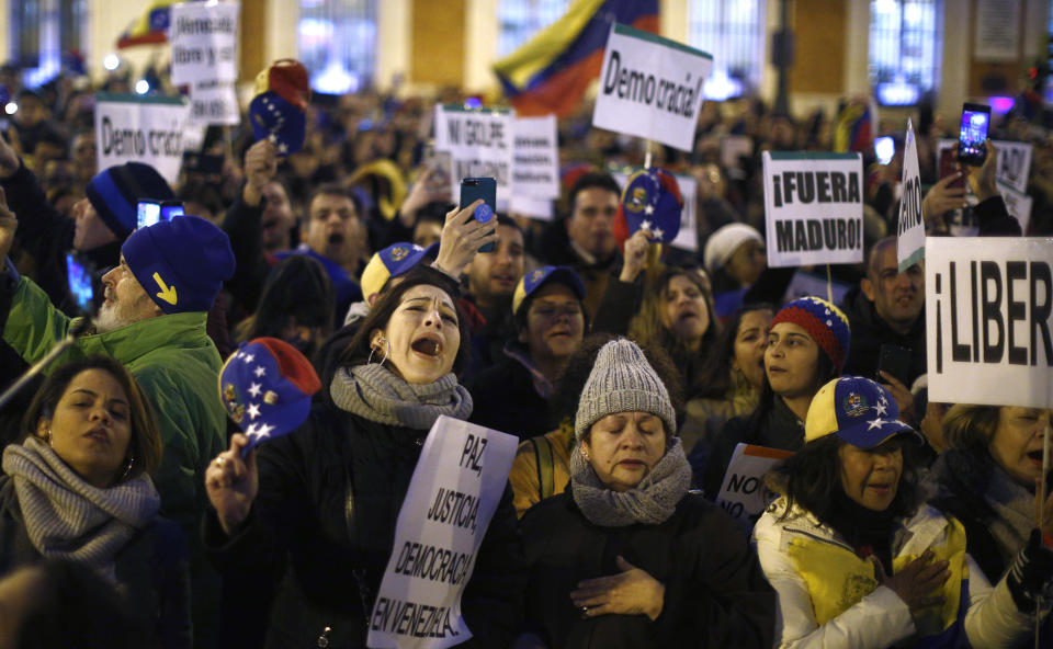 People gather during a protest Venezuela's Nicolas Maduro and in support of an opposition leader self-proclaimed as the interim president of the country in Madrid, Spain, Wednesday, Jan. 23, 2019. Around 7,000 protesters according to organizers, gathered in a central square of the Spanish capital, where a significant Venezuelan community has grown in recent years with people fleeing persecution or poverty at home. Banners reads in Spanish: "Democracy", "Out Maduro", " Peace, Justice, Democracy in Venezuela". (AP Photo/Manu Fernandez)