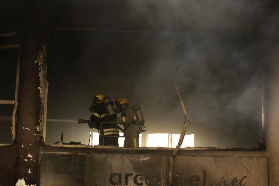 Lebanese firemen extinguish a fire inside a building that were burned in a wildfire overnight, in the town of Damour, just over 15km (9 miles) south of Beirut, Lebanon, Tuesday, Oct. 15, 2019. Strong fires spread in different parts of Lebanon forcing some residents to flee their homes in the middle of the night as the flames reached residential areas in villages south of Beirut. (AP Photo/Hassan Ammar)