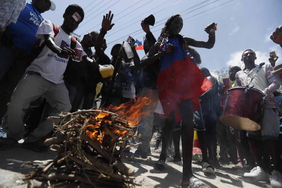 Supporters of former Haitian President Jean-Bertrand Aristide dance and drum as they wait near the airport for his expected arrival from Cuba, where he underwent medical treatment, in Port-au-Prince, Haiti, Friday, July 16, 2021. Aristide's return adds a potentially volatile element to an already tense situation in a country facing a power vacuum following the July 7 assassination of President Jovenel Moïse. (AP Photo/Fernando Llano)