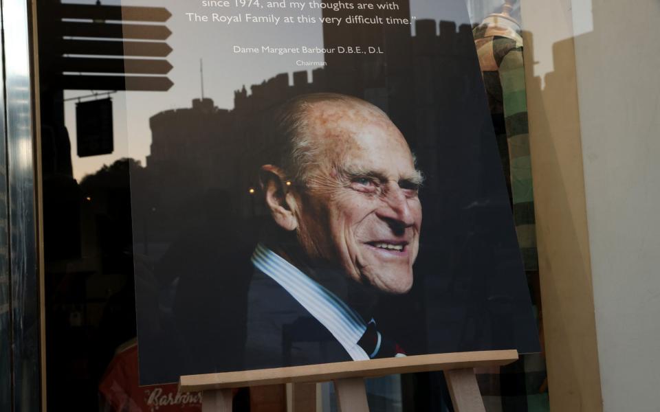 Windsor Castle is reflected in the window of the Barbour store in Windsor, in which a portrait of the Duke of Edinburgh is on display - Chris Jackson