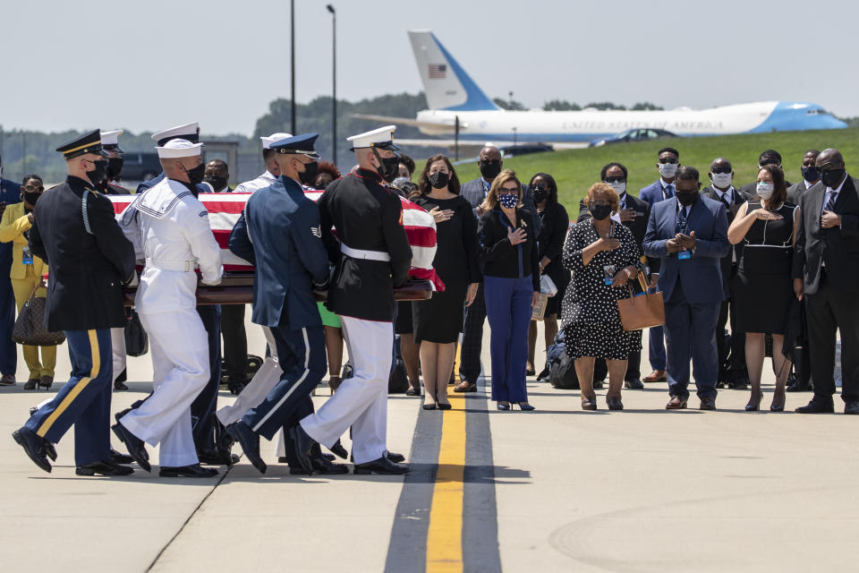 The flag-draped casket of Rep. John Lewis, D-Ga., is carried by a joint services military honor guard with House Speaker Nancy Pelosi of Calif., left and family members standing nearby, Monday, July 27, 2020, at Andrews Air Force Base, Md. The plane that is Air Force One when used by the President is behind them. (AP Photo/Alex Brandon, Pool)