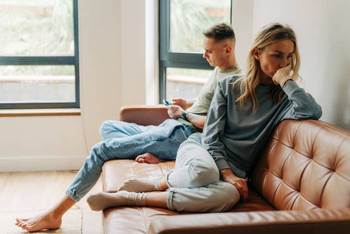 A couple not speaking to each other on the couch