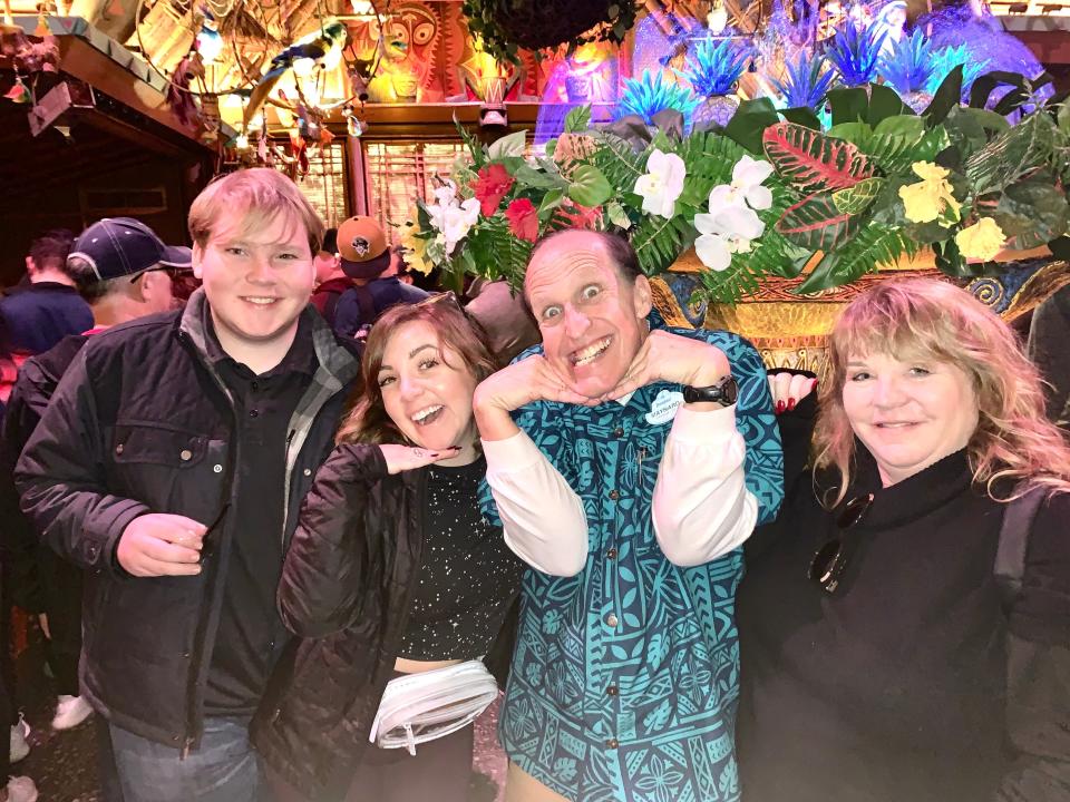 disney guests posing with a park employee in line for a ride at disneyland