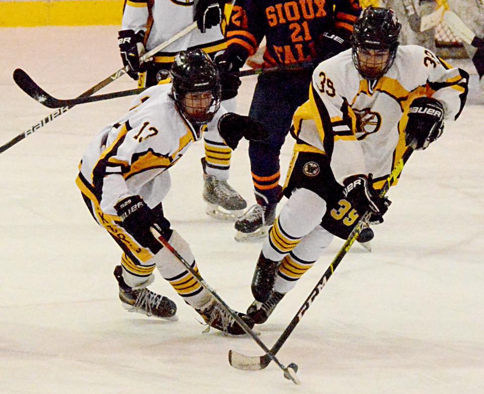 Thomas Foley (13) and Dakota Woertink (39) of the Watertown Lakers attempt to control the puck against the Sioux Falls Flyers I during their South Dakota Amateur Hockey Association varsity boys game Friday night in the Maas Ice Arena.