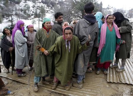 Unidentified relatives of victims react at the site of a damaged house after a hillside collapsed onto a house at Laden village, west of Srinagar, March 30, 2015. REUTERS/Danish Ismail
