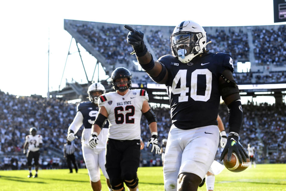 Penn State linebacker Jesse Luketa (40) celebrates after intercepting Ball State quarterback Drew Plitt (9) and returning it for a touchdown in the third quarter of an NCAA college football game in State College, Pa., on Saturday, Sept. 11, 2021. Penn State defeated Ball State 44-13. (AP Photo/Barry Reeger)