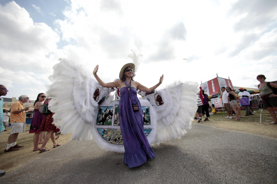 FILE - In this May 1, 2011 file photo, Deanna Bordelon, of Montgomery, Texas, poses for a photo in front of Chief Victor Armstrong of the Golden Blades Mardi Gras Indian tribe, as he and his tribe parade through the Fairgrounds at the Louisiana Jazz and Heritage Festival in New Orleans. April marks the start of spring festival season in south Louisiana. As the revelry of Mardi Gras and chill of winter end, spring festivals usher in the flip-flops, floppy hats and folding chairs toted by music lovers from across the globe. French Quarter Festival and Jazz Fest in New Orleans, and Festival International de Louisiana in Lafayette, La., are all held in April. Other Louisiana festivals held in spring and summer include Bayou Country Superfest in May, New Orleans Cajun-Zydeco Festival in June, Essence Music Festival in July and Satchmo Summerfest in August. (AP Photo/Gerald Herbert, File)