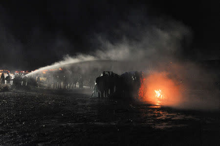 Police use a water cannon to put out a fire started by protesters during a protest against plans to pass the Dakota Access pipeline near the Standing Rock Indian Reservation, near Cannon Ball, North Dakota, U.S. November 20, 2016. REUTERS/Stephanie Keith