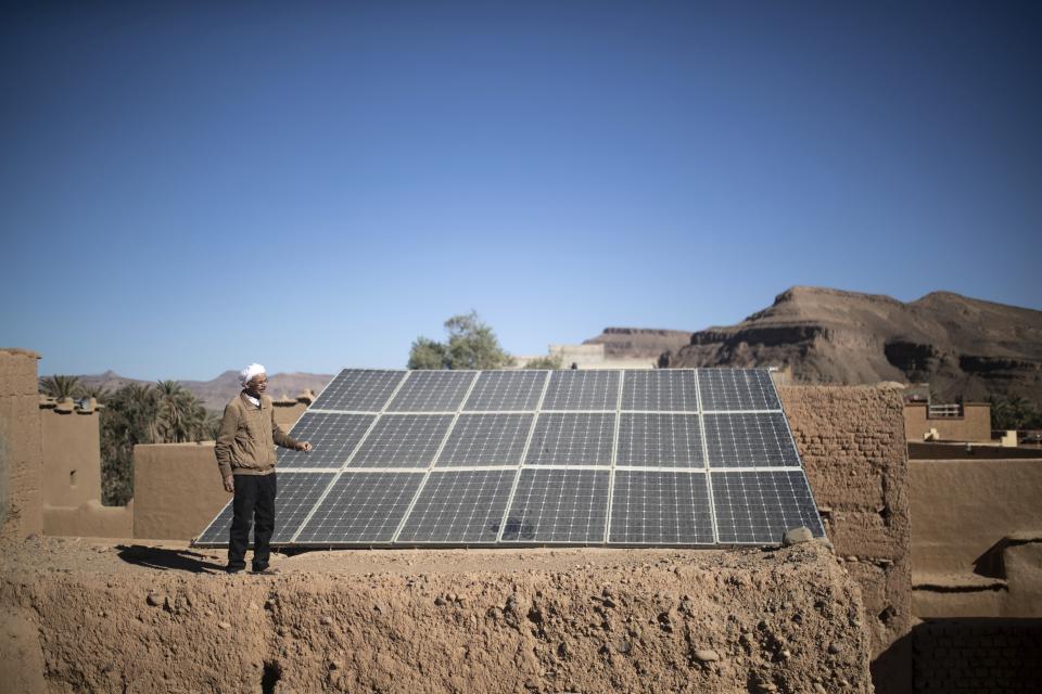 Hassan Bouazza stands next to solar panels that he installed in the Alnif oasis town, near Tinghir, Morocco, Tuesday, Nov. 29, 2022. He was the first to install solar panels on the region’s ksar, or castle, and began relying on the energy produced to dig wells and irrigate his fellow farmers’ lands. (AP Photo/Mosa'ab Elshamy)