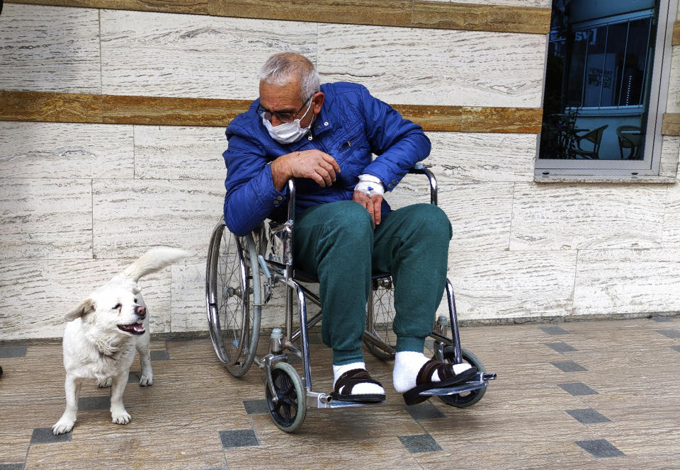 Cemal Senturk, owner of Boncuk, outside of a medical care facility in the Black Sea city of Trabzon, Turkey, Wednesday, Jan. 20, 2021. Boncuk has spent five days waiting in front of the hospital where her sick owner was receiving treatment. Senturk was discharged from the hospital later on Wednesday and returned home with Boncuk.(DHA via AP)